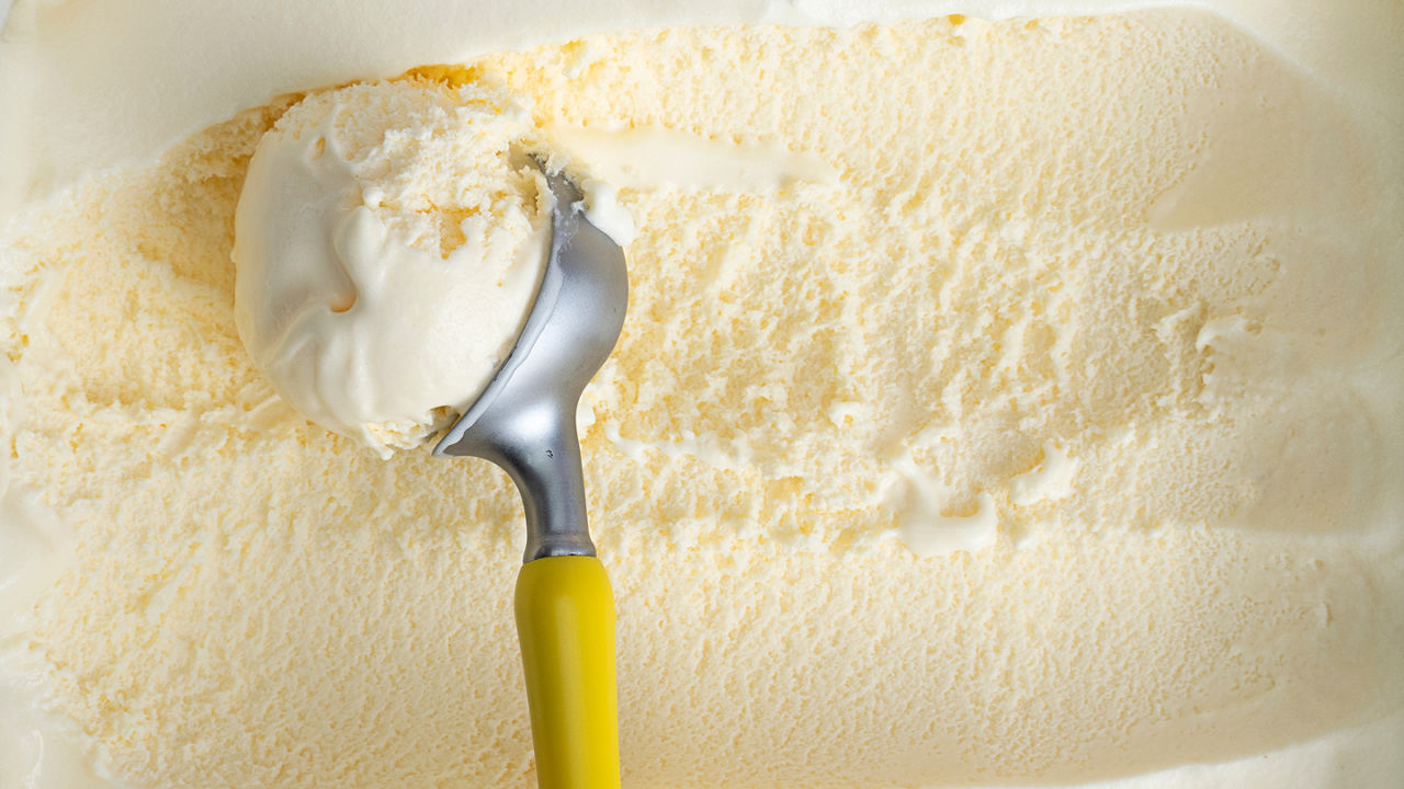 Vanilla ice cream being scooped out of a container