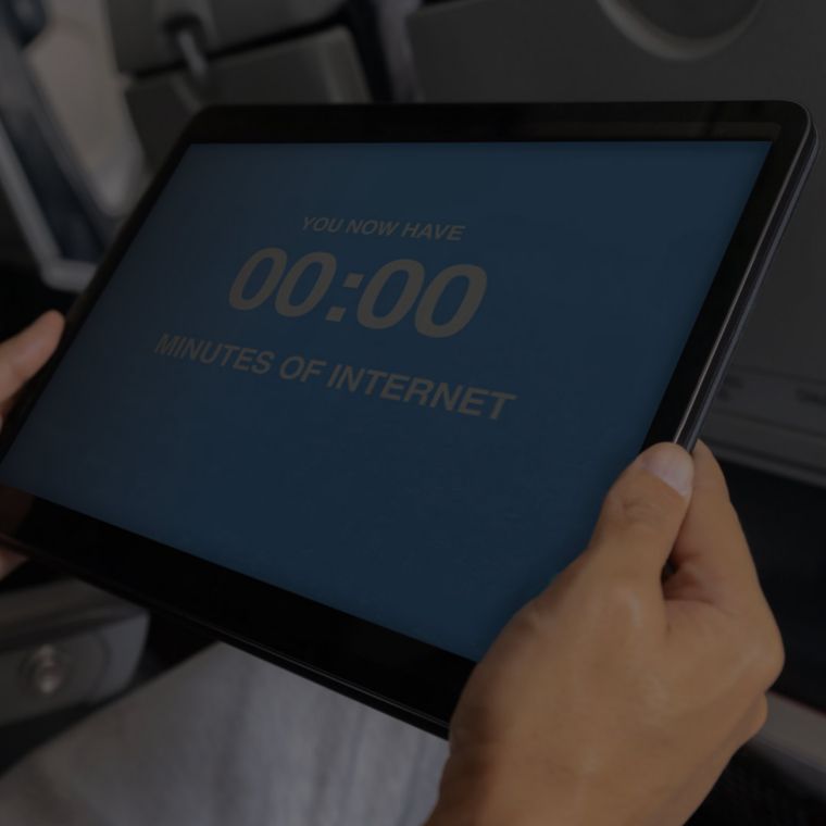 In a row of airplane seats, a person holds a tablet.