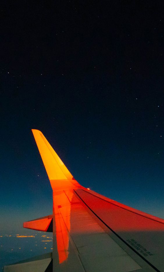 An airplane wing is lit up against a night sky.