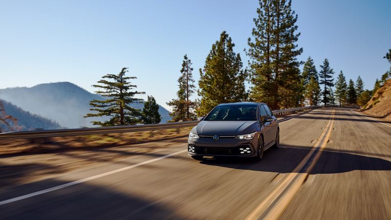 The 2022 Volkswagen Golf GTI driving down a roadway. 