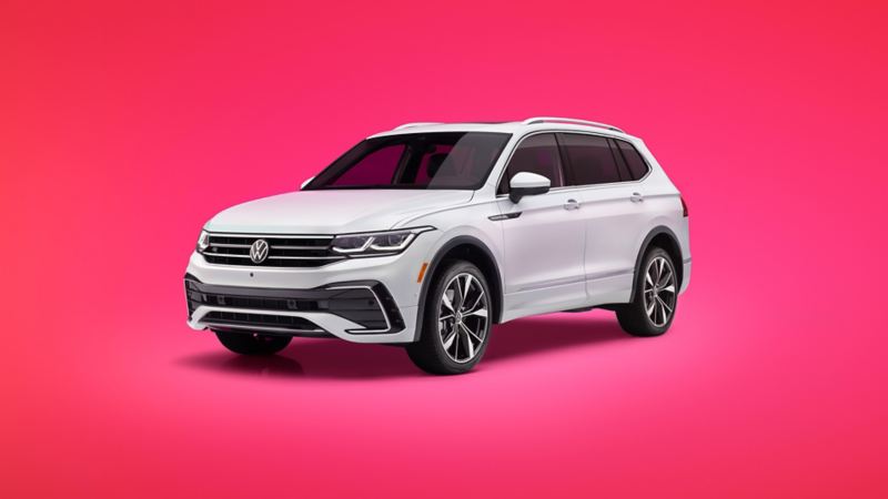 A three-quarter, front view of a Tiguan shown in Opal White on a vibrant, rose gradient background.