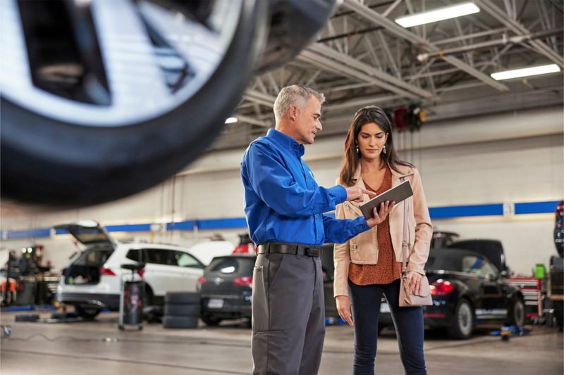 Standing inside a service center garage an interested customer speaks with a Volkswagen sales/product specialist at a dealership.