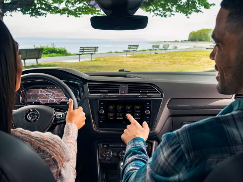 Young couple views scenic lake through the windshield of their Volkswagen Tiguan—complete with impressive interior tech.