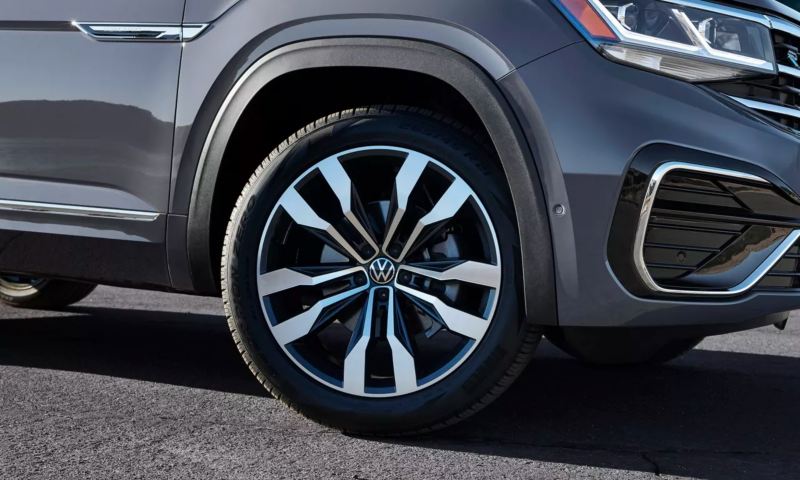 A sharply lit angle of a platinum gray metallic Volkswagen Atlas Cross Sport showcases its passenger’s side R-Line wheel.