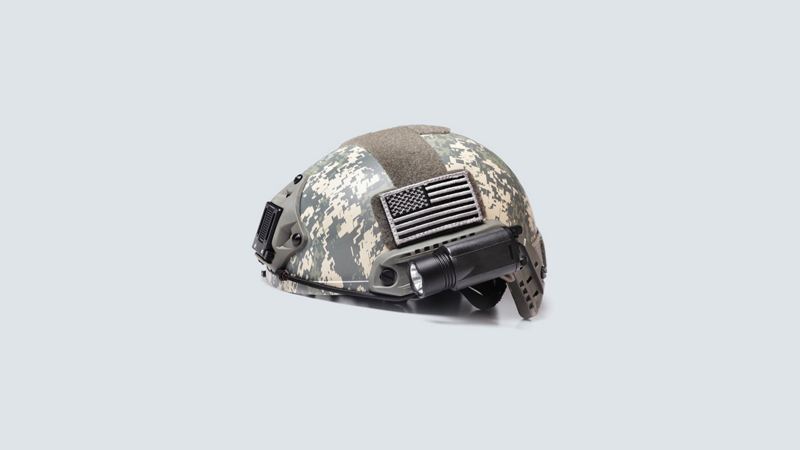 A camo helmet with a flashlight and flag patch