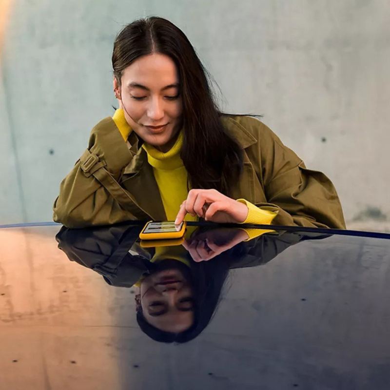 A stylishly dressed woman gazes at her smartphone.