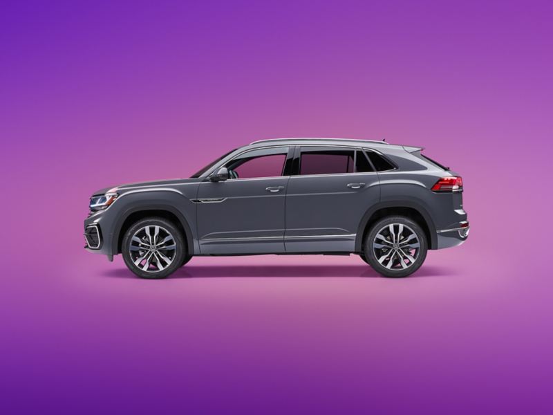 A driver’s side profile view of an Atlas Cross Sport shown in Pure Gray on a vibrant, purple gradient background.