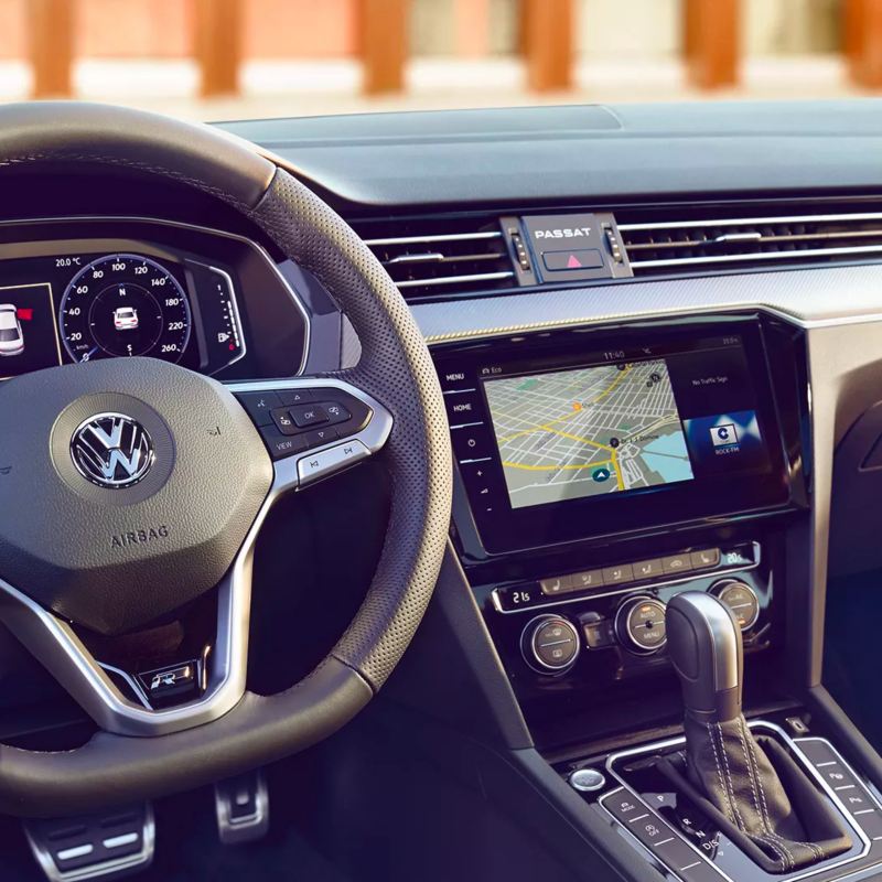 Toma del lujoso interior del Passat de Volkswagen que muestra el tablero digital, el sistema de navegación con pantalla táctil y la palanca de cambios en piel.