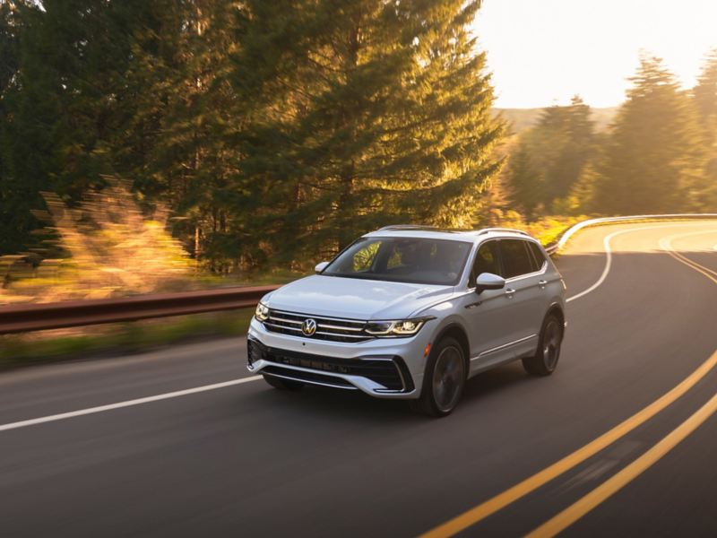 2023 VW Tiguan, shown in Opal White, driving on a winding road.