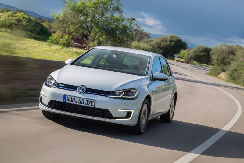 A man drives the 2013 Volkswagen e-Golf down the road showing front ¾ view of the vehicle.