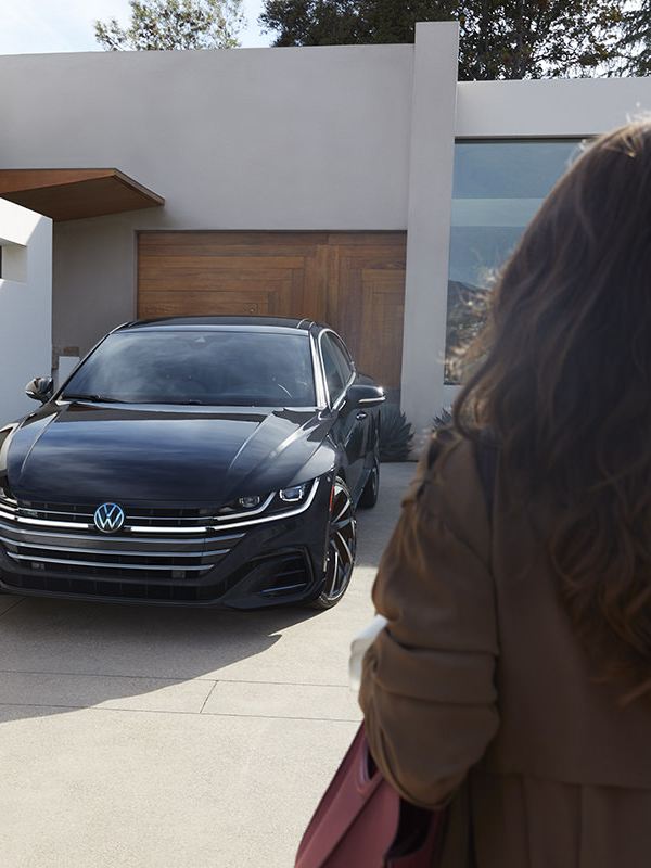 Arteon shown in Deep Black Pearl parked in the driveway of a modern home.