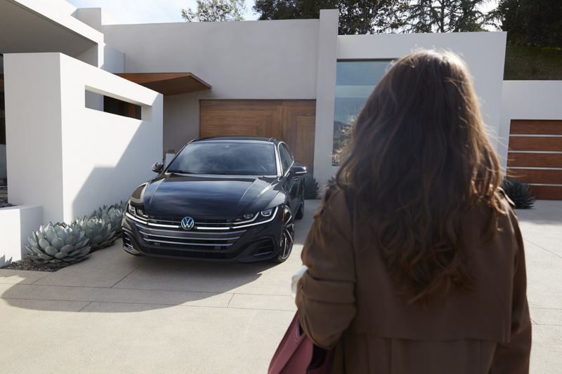 Arteon shown in Deep Black Pearl parked in the driveway of a modern home.