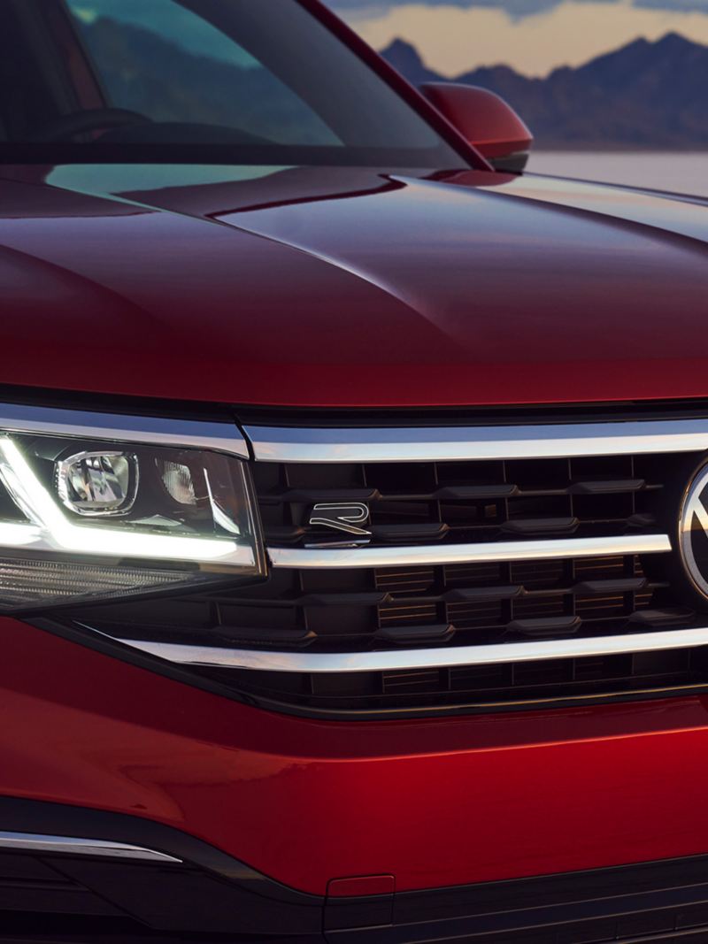 Close-up of the LED headlights and grill on an Atlas Cross Sport in Aurora Red Metallic.