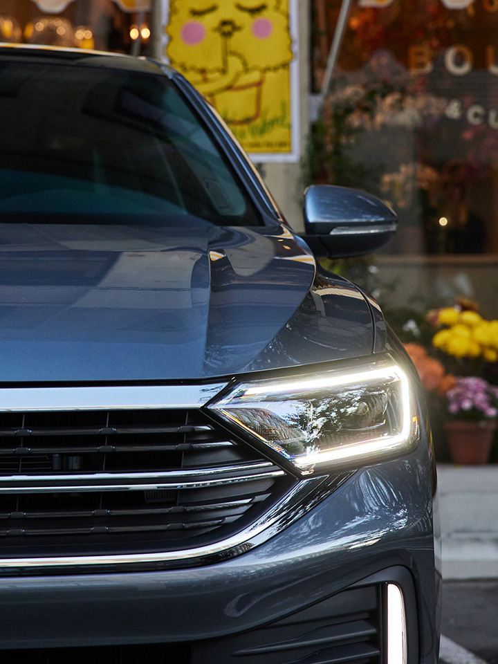 Close up shot of LED headlight on a Jetta shown in Platinum Gray Metallic parked in front of a florist.