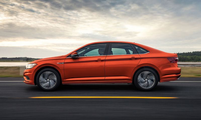 A driver’s side profile of the Jetta shown in Habanero Orange Metallic in motion.