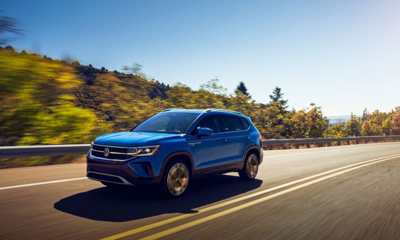 A Taos in Cornflower Blue drives on a two-lane highway.