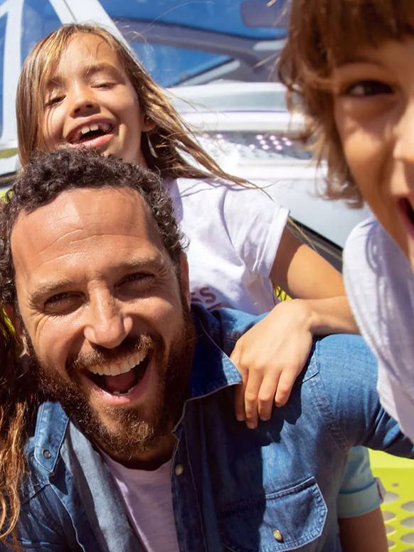 Un hombre, su esposa y dos hijas posan para una selfie frente a su Volkswagen.