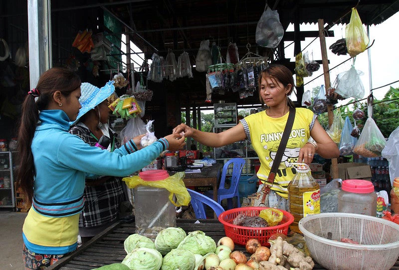 A woman purchases vegetables from a market sellet at Sambok village in Cambodia