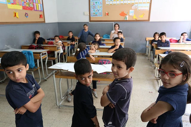 Syrian refugee students listen to their school teacher during math classes