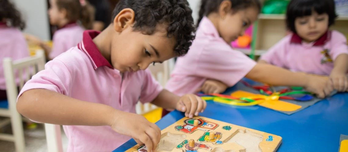 Children play with learning puzzles in a school room.