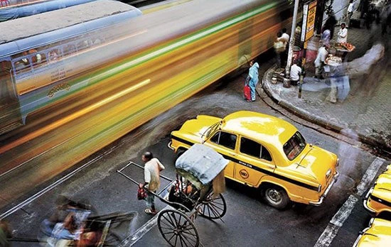 A hand-drawn richshaw wallah stands beside an old Ambassador taxi at the intersection of Madan Street and Lenin Sarani in Chandni Chowk. © Martin Roemers/Panos