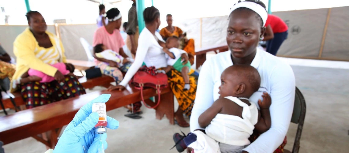 Jestina Wright a nurse (hands in far left) prepares to vaccinate children at Redemption Hospital in Monrovia, Liberia 