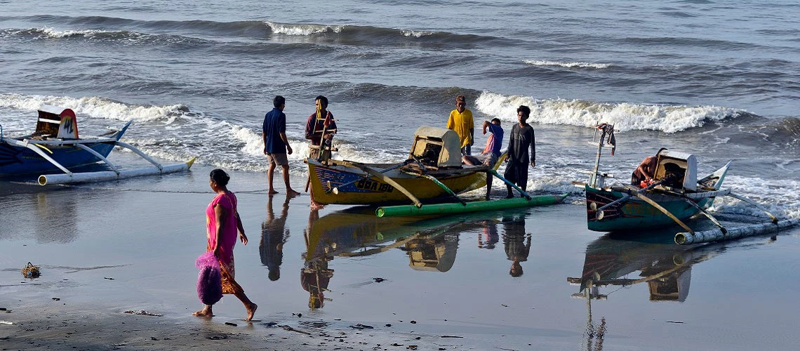 Fishermen from Tanah Beru Village in Indonesia preparing their boats by the sea.