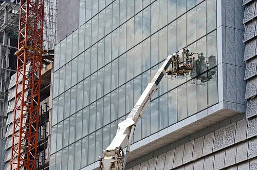 A construction worker finishes sealing glass, Kuala Lumpur, Malaysia. Photo credit: Flickr @World Bank Photo Collection