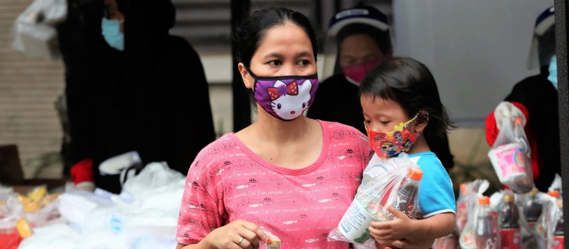 Une mère et sa fille reçoivent de l'aide alimentaire pendant la pandémie de COVID-19 à Jakarta (Indonésie). Photo : Achmad/Banque mondiale
