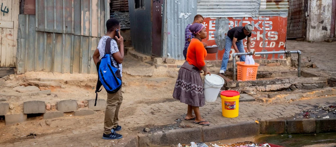 People washing their clothes along the roadside in front of an informal settlement in Johannesburg, South Africa.