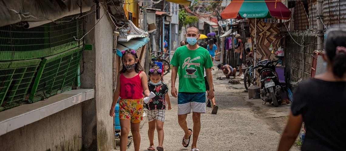 Man and two girls walking in a neighborhood in the Philippines. ©Ezra Acayan/World Bank