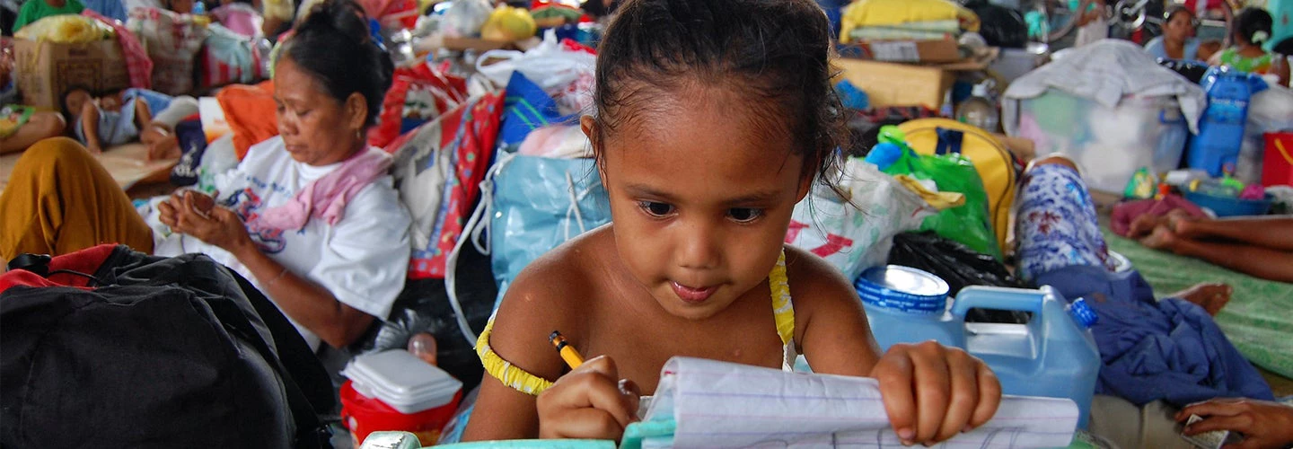 Young girl doing schoolwork in a refugee camp