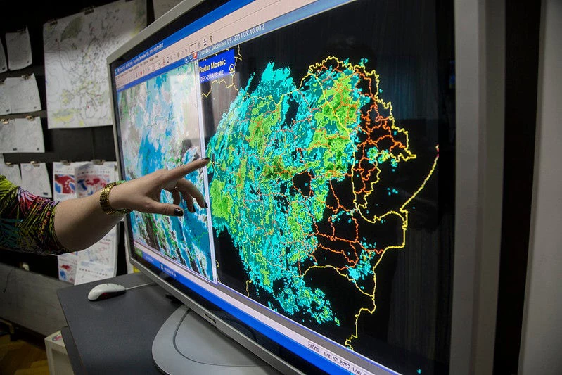 A finger points to a map on a computer screen, labeled Radar Mossaic