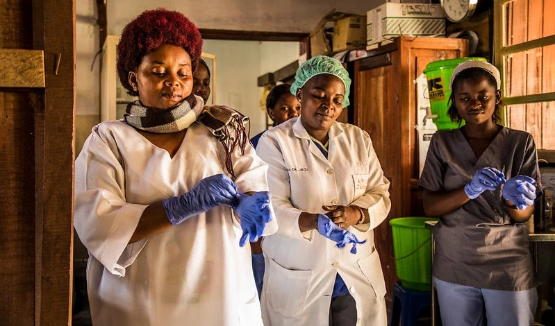 Health workers put their gloves on before checking patients at the hospital; DRC