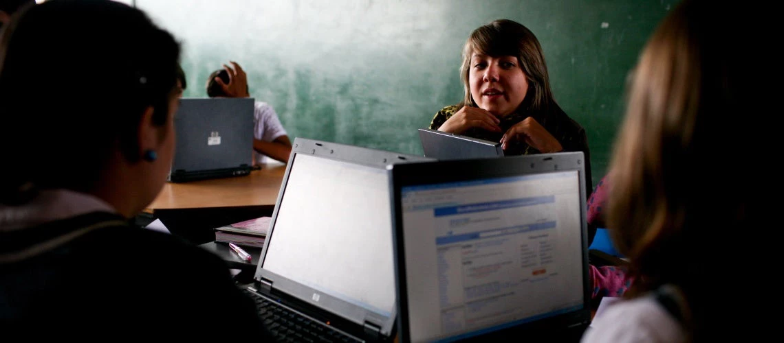 A teacher guides high school students in a technical education class