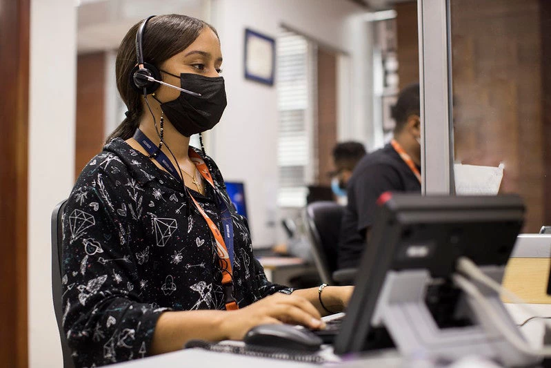 Mujer con tapabocas trabajando en una computadora de escritorio. 