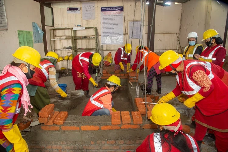 Women mason learning brick-layering skills. 