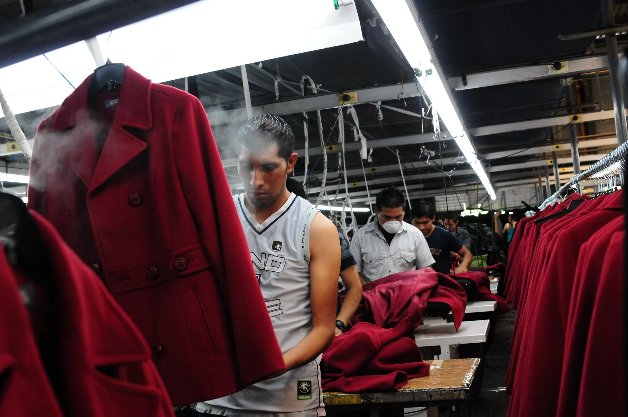 Men assemble women's coats in a manufacturing factory