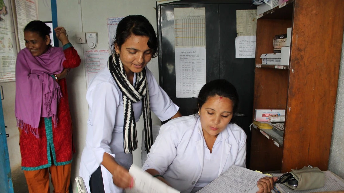 Staff at a rural health clinic consult as a patient waits her turn in rural Nepal