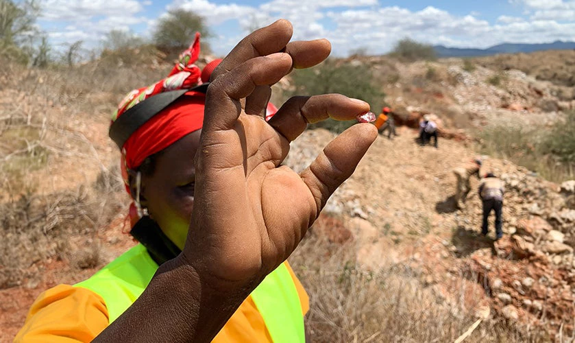 A woman artisanal miner displaying a gem she extracted.