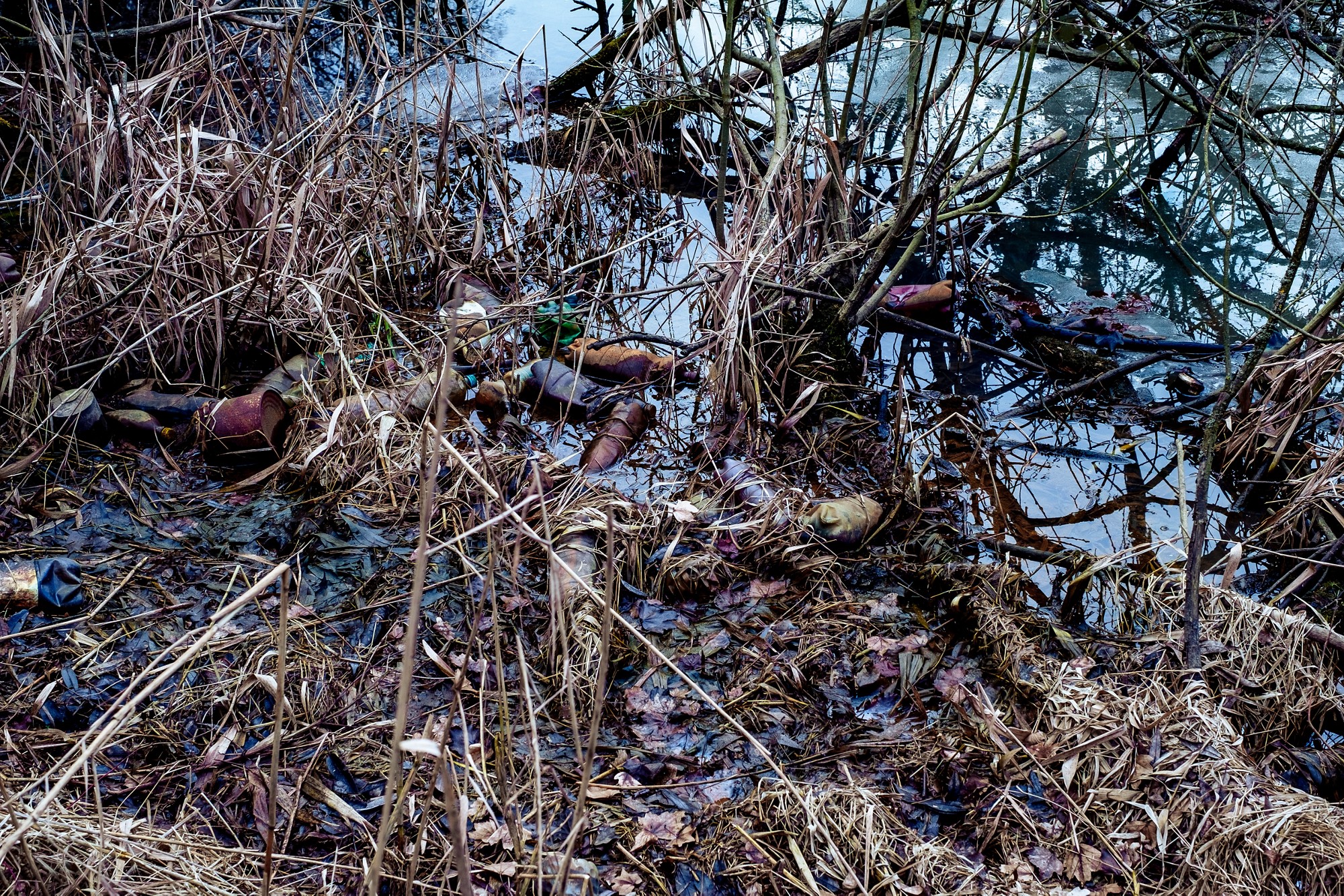Various kinds of trash waste objects a lot floating in the pond mixed with aquatic plants