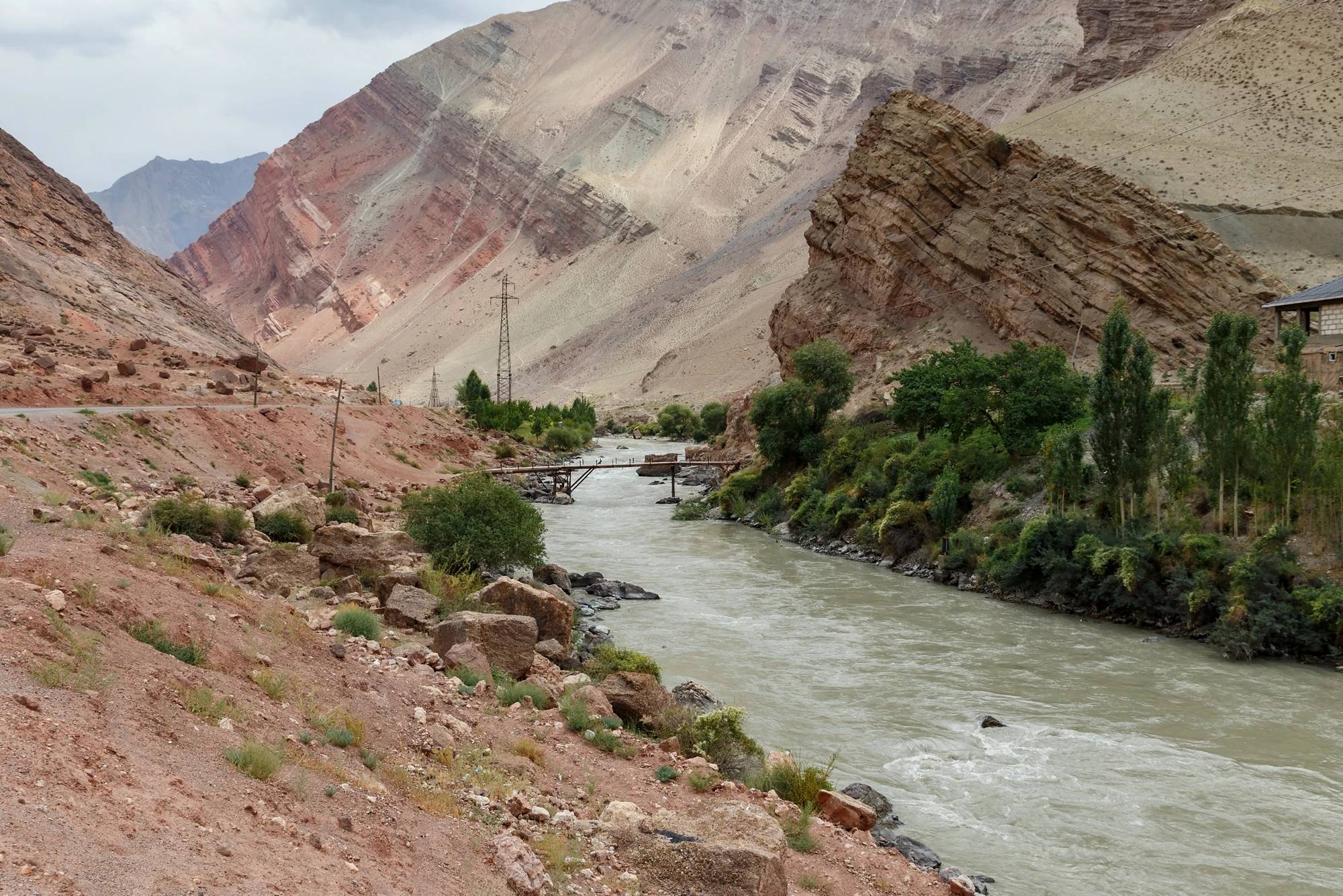 Lush vegetation lines the Yaghnob River as it winds through dramatic mountain landscapes in Tajikistan.