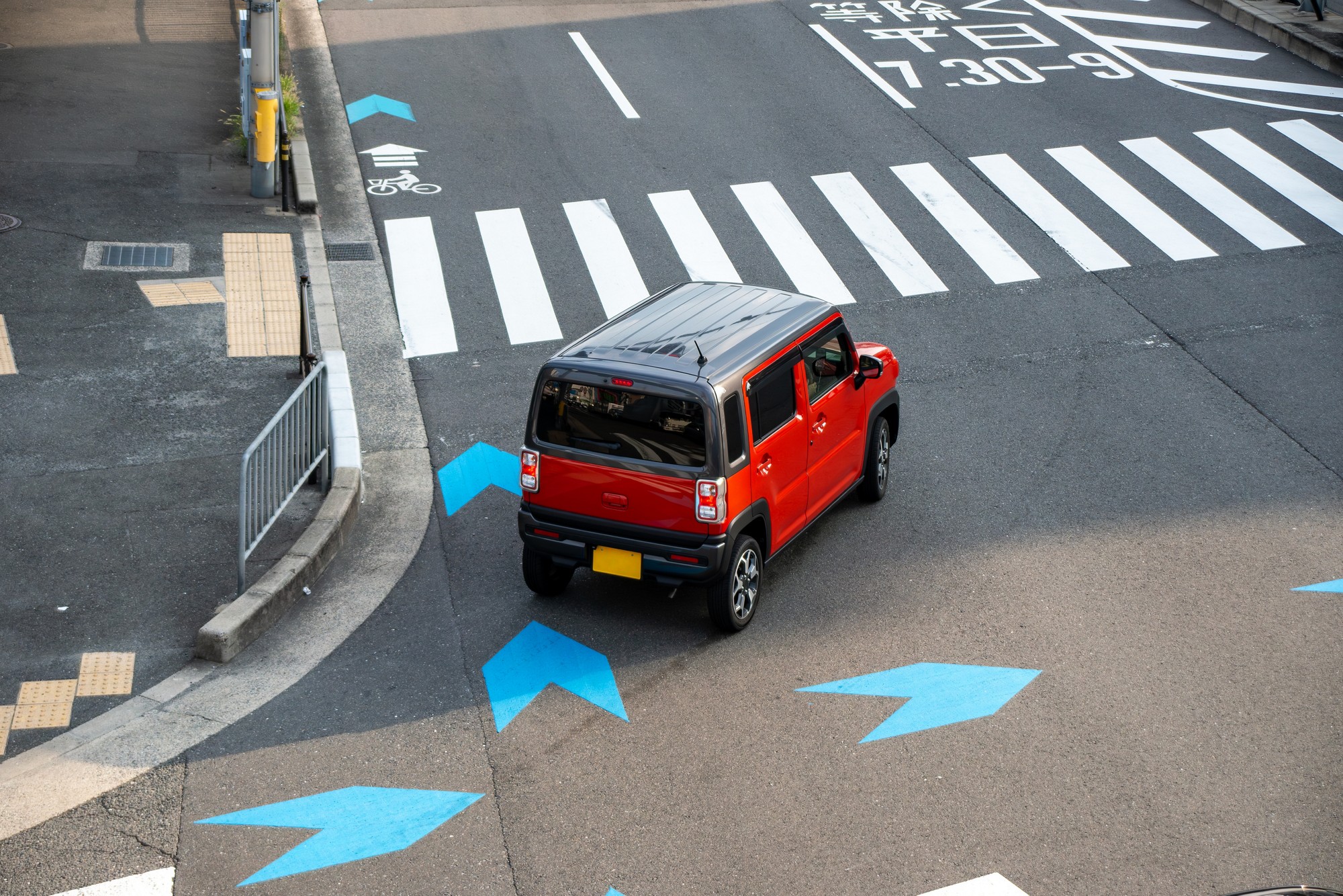 交差点を左折して横断歩道に差し掛かる軽自動車