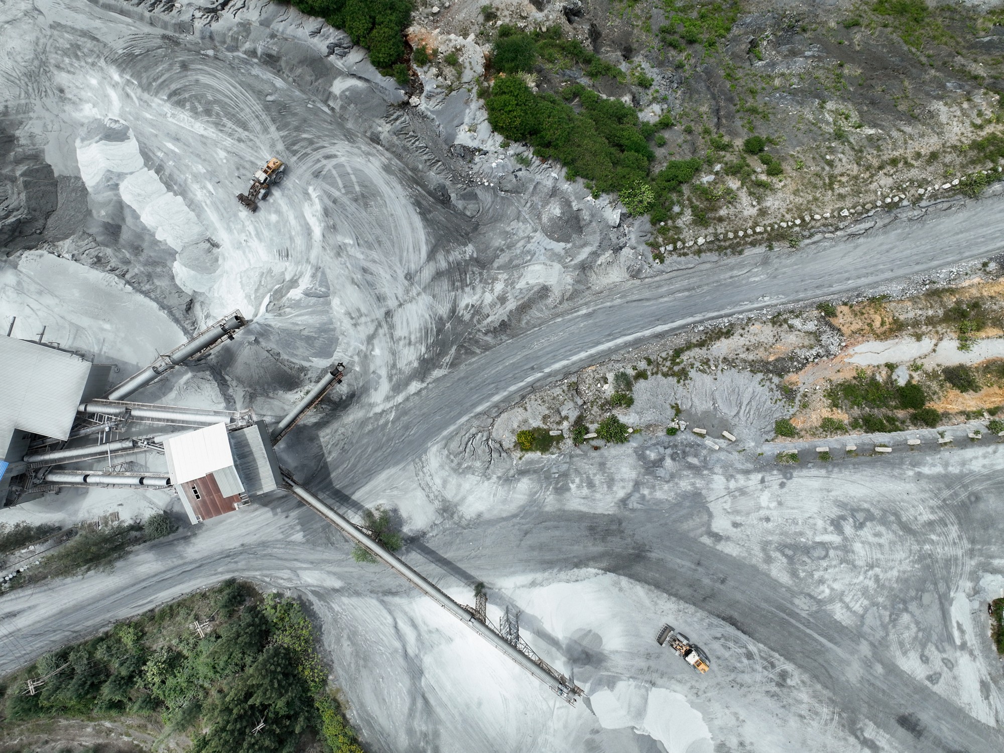 Quarry facility with visible impact on landscape and machinery in full operation, emphasizing the environmental challenges of sustainable material sourcing in modern construction industries.
