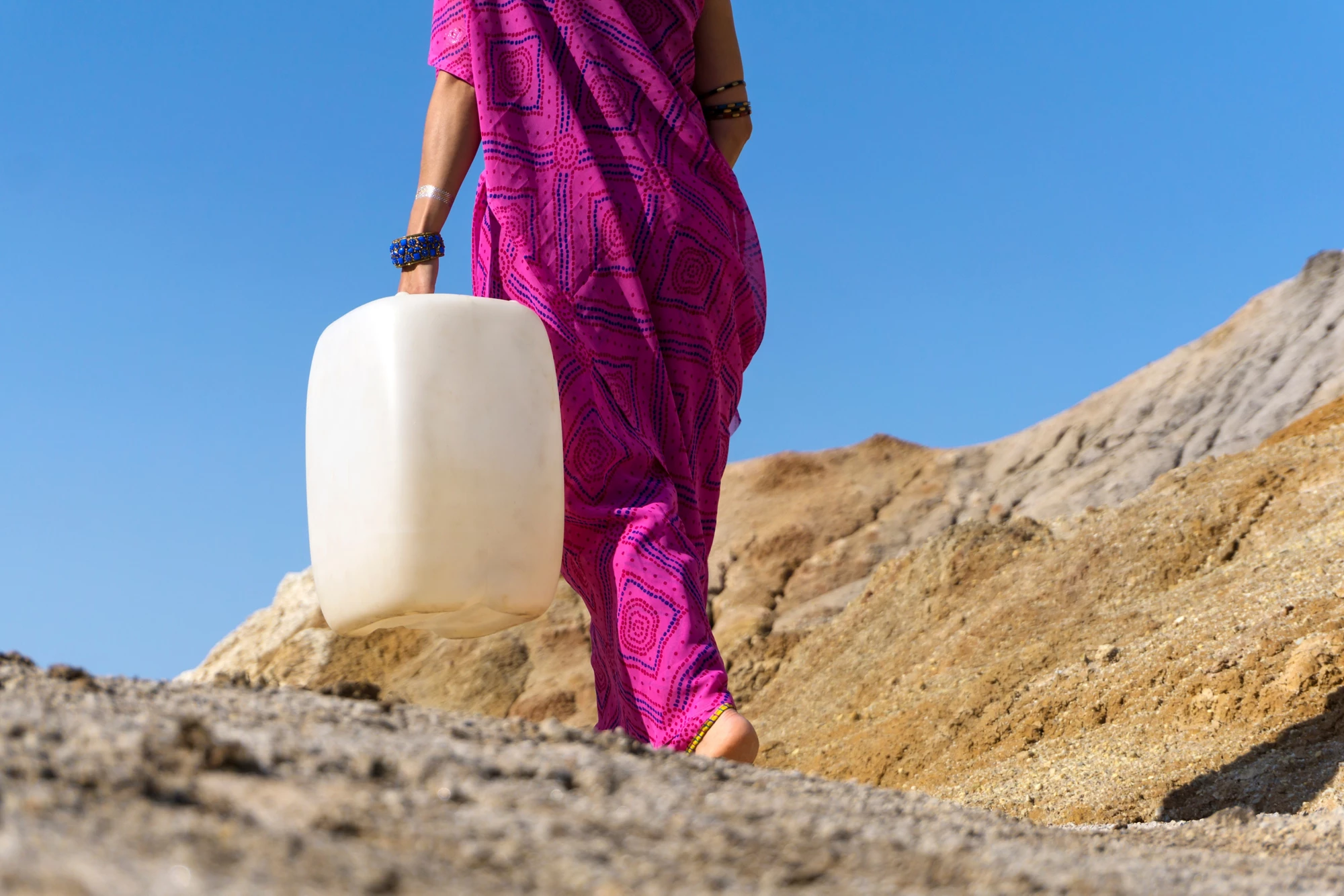 a girl in ethnic clothing goes for water with a plastic jerrican