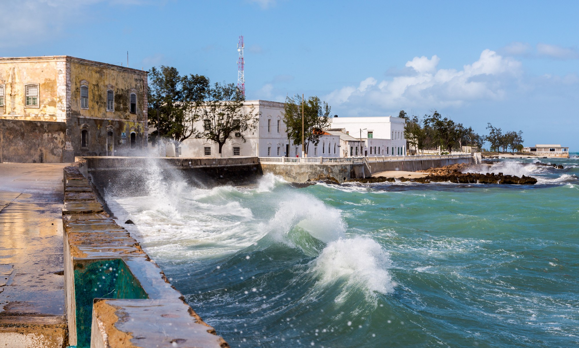 Ocean waves crash over a seawall to seafront embankment. Mozambique island (Ilha de Mocambique), Indian ocean coast, Moçambique. Mozambique Channel, Mossuril Bay, Nampula Province. Portuguese Africa