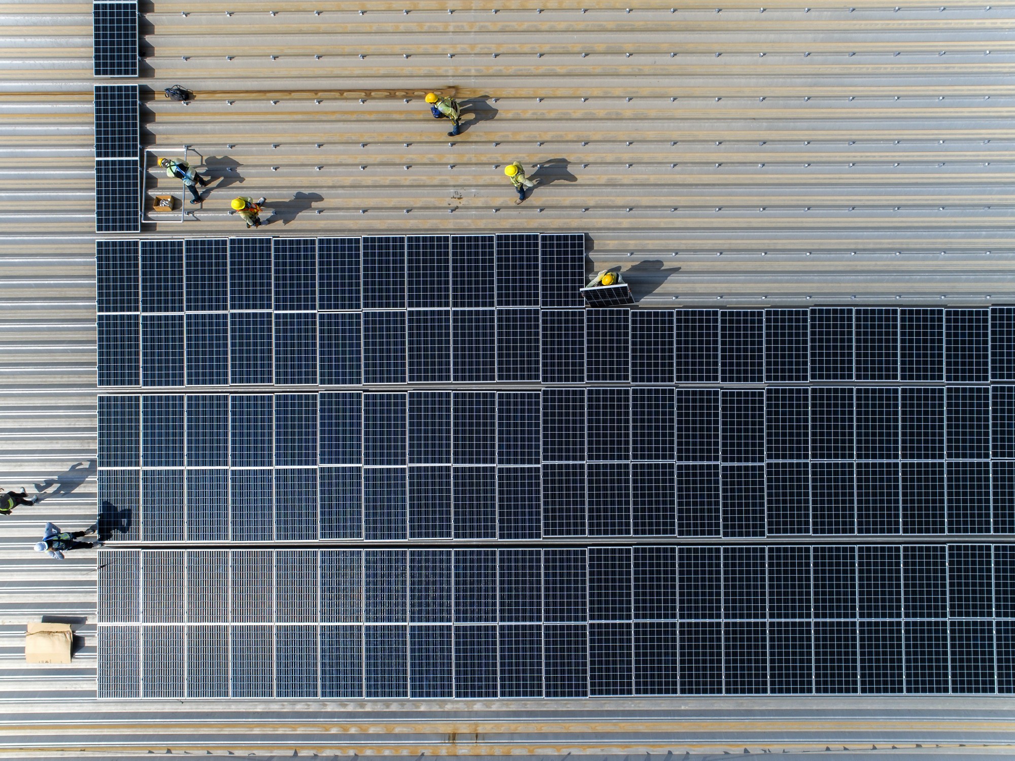 top view worker installing a solar cell on the factory roof.