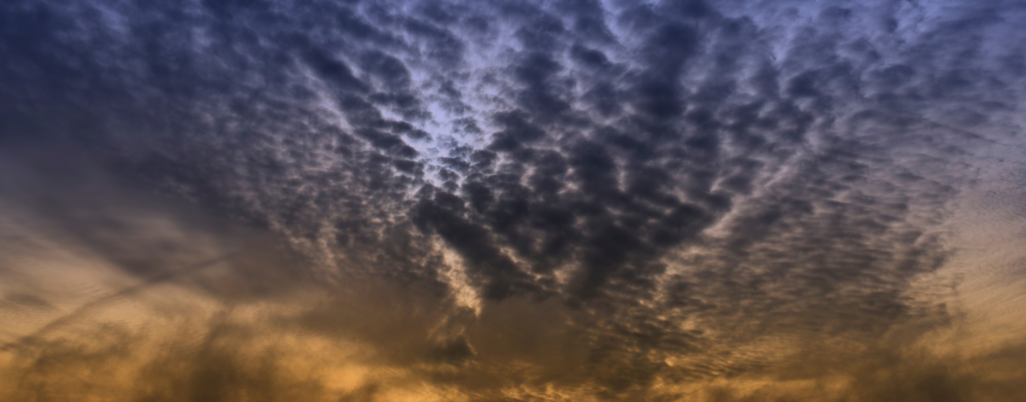 Dramatic evening sky with interesting cloud structure. Color gradient from orange to dark blue. Interesting background with space for your design.