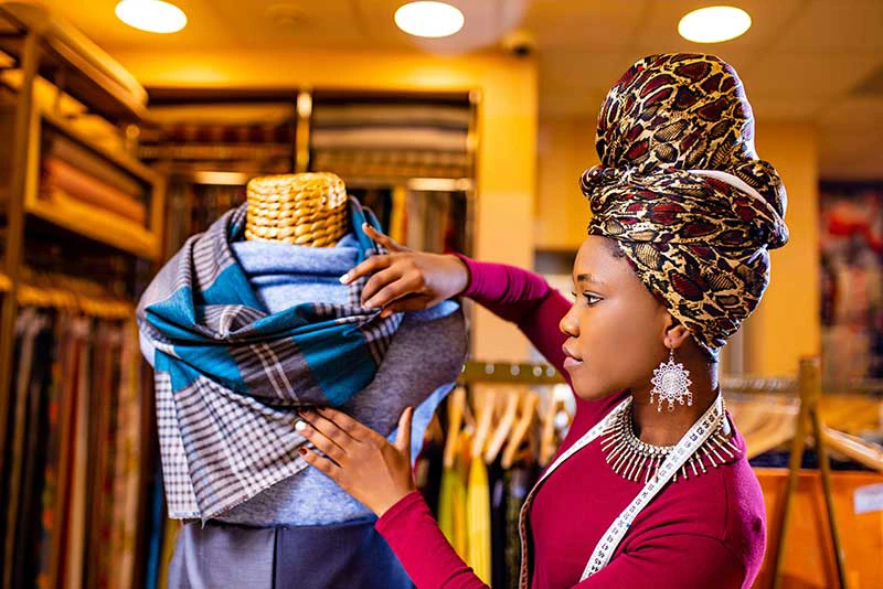 African saleswoman sets up a cotton and lace fabric showroom. Photo: Shutterstock.com
