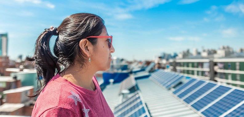 Mujer mirando paneles solares en Barrio 31, Argentina. 